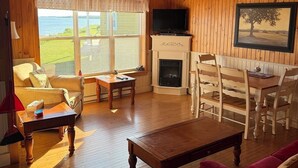 Una sala de estar acogedora con paredes de madera, una chimenea, un televisor y un comedor.