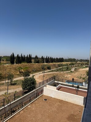 A rooftop terrace with a view of a landscaped area, a swimming pool, and a clear sky. - K-Home 3 Bedrooms Karmei Gat - Kiriat Gat (קריית גת)