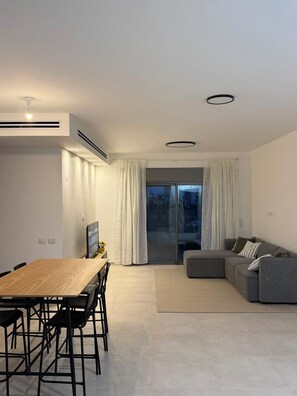En moderne opholdsstue med spiseplads, sofa og et stort vindue.