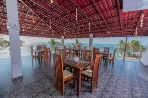 An outdoor dining area with tables and chairs, a stone floor, and a view of the ocean. - Dutch Point Beach Resort - Negombo (Negombo)