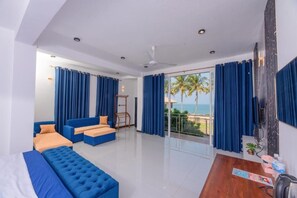 A modern room with a sofa, a bed, a wooden table, and a balcony with a view of the sea. - Dutch Point Beach Resort - Negombo (Negombo)