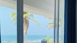 A room with a large window overlooking a beach with palm trees and the ocean. - Dutch Point Beach Resort - Negombo (Negombo)