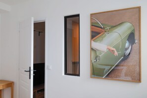 Ein Zimmer mit einer Tür, einem gerahmten Gemälde eines Autos und einem kleinen Tisch.