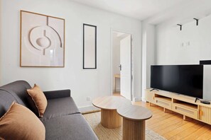Ein modernes Wohnzimmer mit einem grauen Sofa, einem Flachbildfernseher und einem Couchtisch aus Holz.