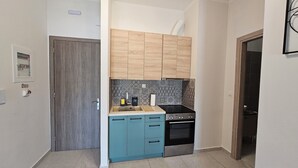 Een kleine keuken met een inbouwoven, een koffiezetapparaat en een spoelbak.