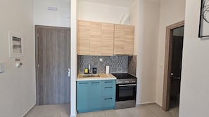 Eine kompakte Küche mit Backofen, Kaffeemaschine und Spüle.