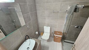 Et badeværelse med vask, toilet og bruser.
