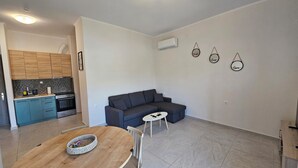 Een modern appartement met een keuken, een grijze bank, een eettafel en een klein witte tafeltje.