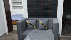 A grey sofa with a glass coffee table in a room with a tiled wall and a door leading to another room. - 2kms  to hawamahal homestay in jaipur (Jaipur)