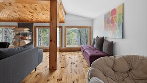 A modern living room with a wooden ceiling, large windows, a sofa, and a chair.
