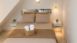 Une chambre avec un plafond en pente, un lit avec une tête de lit, des tables de chevet, un luminaire fixé au mur et une suspension.