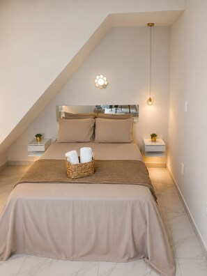 A bedroom with a sloped ceiling, a bed with a headboard, bedside tables, a wall-mounted light fixture, and a hanging pendant light. - Ap Favela Chic, very cozy. With a hot tub and barbecue, 700 meters from the beach. (Rio de Janeiro)