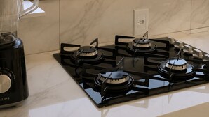 Une cuisine équipée d’une cuisinière à gaz, d’un mixeur et d’une fenêtre donnant sur la mer et les bâtiments.
