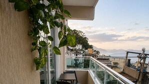 Un balcon avec une table et des chaises, une balustrade en verre et une vue sur le paysage urbain.