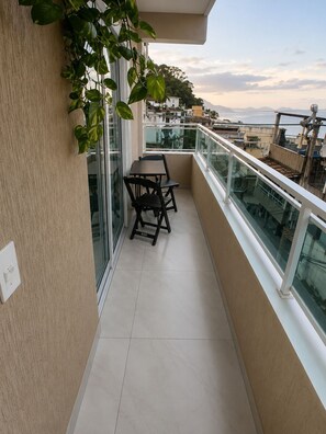 A balcony with a table and chairs, glass railings, and a view of the cityscape. - Ap Favela Chic, very cozy. With a hot tub and barbecue, 700 meters from the beach. (Rio de Janeiro)