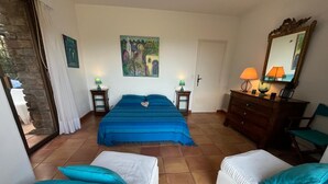 Ein Schlafzimmer mit einem Bett, zwei Nachttischen, einer Kommode, einem Sessel, einem Spiegel und einem Bild an der Wand.