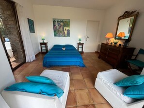 Ein Schlafzimmer mit einem Bett, zwei Nachttischen, einer Kommode, einem Sessel, einem Spiegel und einem Bild an der Wand.