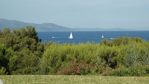 Eine Küstenlandschaft mit klarem Blick auf das Meer, Segelbooten und entfernten Hügeln.
