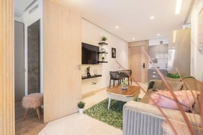 Ein modernes Wohnzimmer mit Sofa, Couchtisch, Fernseher und Essbereich.