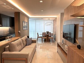 Ein modernes Wohnzimmer mit einer Couch, einem Esstisch und einem Fernseher.