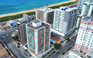 Ein Hochhaus mit mehreren Etagen, einer Dachterrasse und Blick auf den Strand.