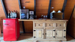 A compact kitchenette with a red refrigerator, a coffee maker, a microwave, and a small sink.