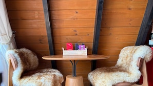 A cozy room with wooden walls, a round wooden table, and two furry chairs.