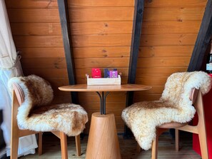 Une pièce chaleureuse aux murs en bois, avec une table ronde en bois et deux fauteuils confortables.