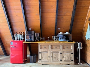 Een kleine keuken met een houten plafond, een rode koelkast, een koffiezetapparaat, een magnetron en een spoelbak.