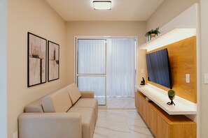 Ein modernes Wohnzimmer mit einer Couch, einem Fernseher und Kunstwerken an der Wand.