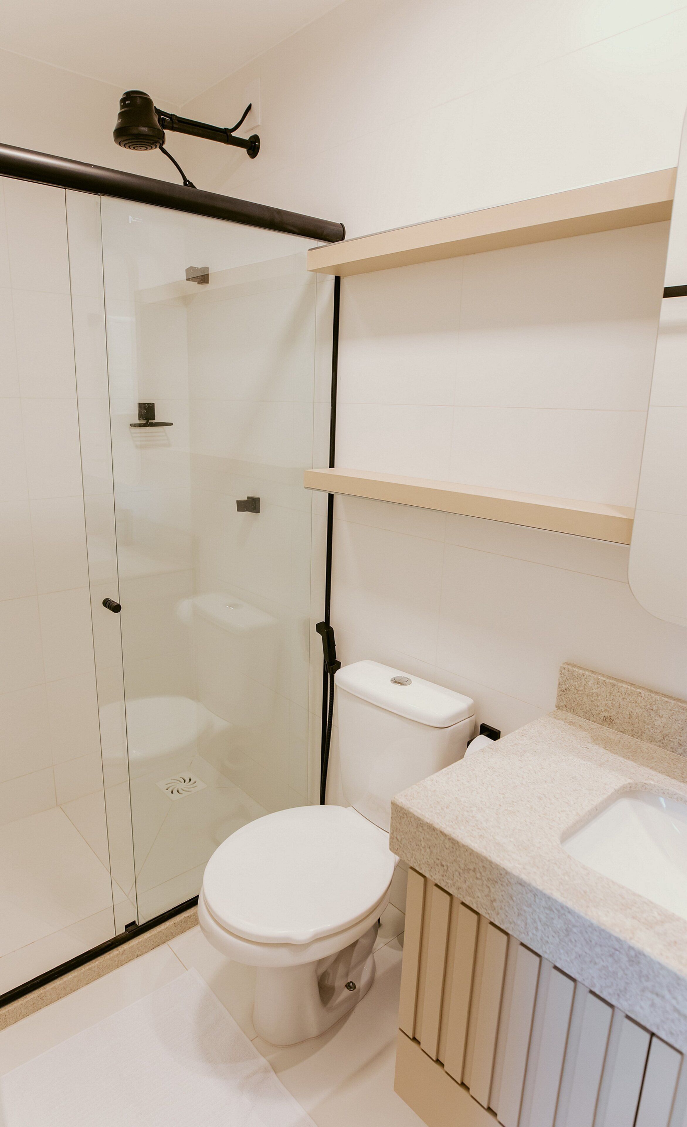 Un bagno moderno con cabina doccia in vetro, un water e un lavabo con piano in granito.