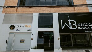 Un edificio a grattacielo con un design architettonico moderno, caratterizzato da un ingresso evidente e uno spazio commerciale al piano terra.