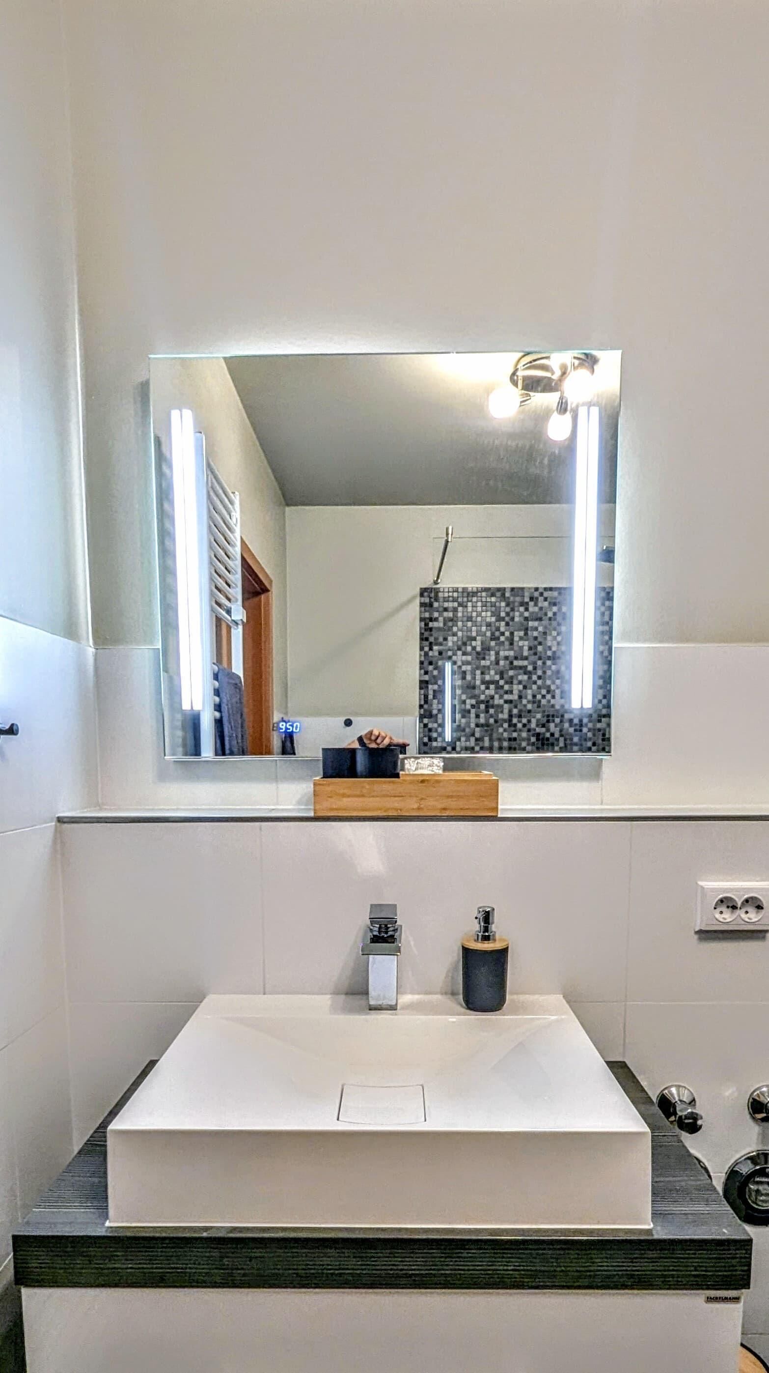 A bathroom with a white sink, a mirror, and a tiled backsplash.