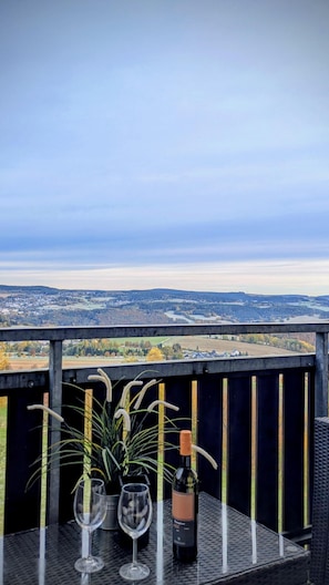 Ein Balkon mit Tisch, zwei Weingläsern und einer Weinflasche.