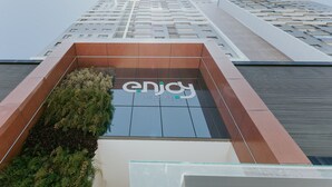 Um edifício moderno com um destaque para o letreiro 'enjoy', fachada de vidro e design estruturado.