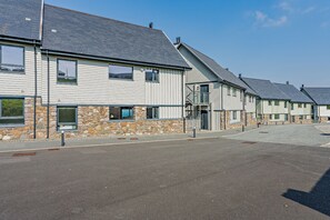 Une rangée d’immeubles modernes à plusieurs étages, dotés de fondations en pierre et de toits gris.