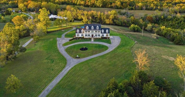 A large, two-story house with a symmetrical facade, a central driveway, and a circular lawn feature. - Southern Winds Bourbon Trail Retreat (Lawrenceburg)