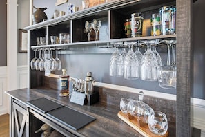 Eine Barbereich mit Regalen, die Gläser, Flaschen und einen Cocktail-Shaker beherbergen.