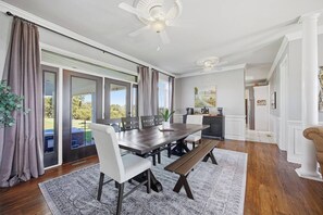 A dining area with a large table, chairs, a bench, a ceiling fan, and a view through glass doors to the outdoors. - Southern Winds Bourbon Trail Retreat (Lawrenceburg)