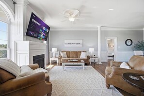Ein Wohnzimmer mit Kamin, Wand-Fernseher, Deckenventilator und Wanduhr.