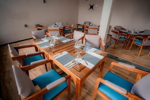 Un salón de conferencias con mesas y sillas de madera, dispuesto para reuniones.