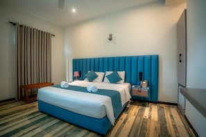 Een hotelkamer met een groot bed, nachtkastje, lamp en een telefoon aan de muur.