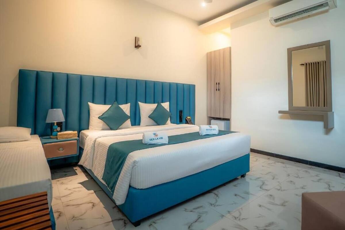 A hotel room with a large bed, a nightstand, a lamp, a wardrobe, and a mirror.