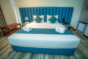 Hotelkamer met een groot bed, nachtkastje met een lamp, een klein tafeltje en een aan de muur bevestigd telefoontoestel.