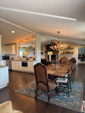 A spacious kitchen with modern appliances, a dining area with a large wooden table and chairs, and a unique antler chandelier.