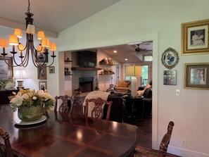 A dining area with a chandelier, a fireplace, and a television.