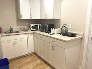 A kitchen with white cabinets, a microwave, a toaster, and a kettle on the countertop. - Basement Queen Bedroom-E（Private Room，Shared Bathroom） (Greater Sudbury)