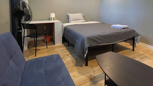 A bedroom with a bed, a desk, a chair, and a table. - Basement Queen Bedroom-E（Private Room，Shared Bathroom） (Greater Sudbury)