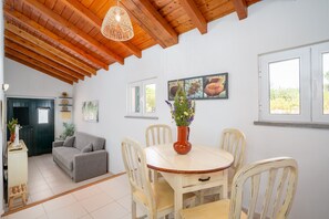 Ein Essbereich mit einem Holztisch und Stühlen, einer Blumenvase und einem Bild an der Wand.
