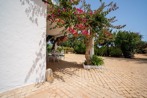 Ein gepflasterter Innenhof mit einer weißen Mauer, einem Tisch mit Stühlen und einem Blumentopf.